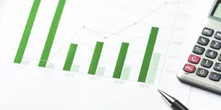 Powiększ obraz: A sheet of paper with graphs, parts of a calculator and a pen